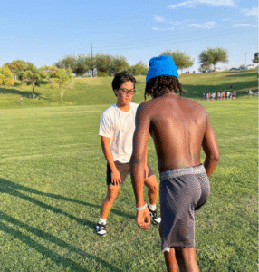 Two athletes running a drill together on a grass field