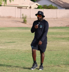 Coach DeShown Johnson Sr standing on a grass practice field