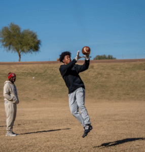 Young athlete leaping to catch a football on an open field